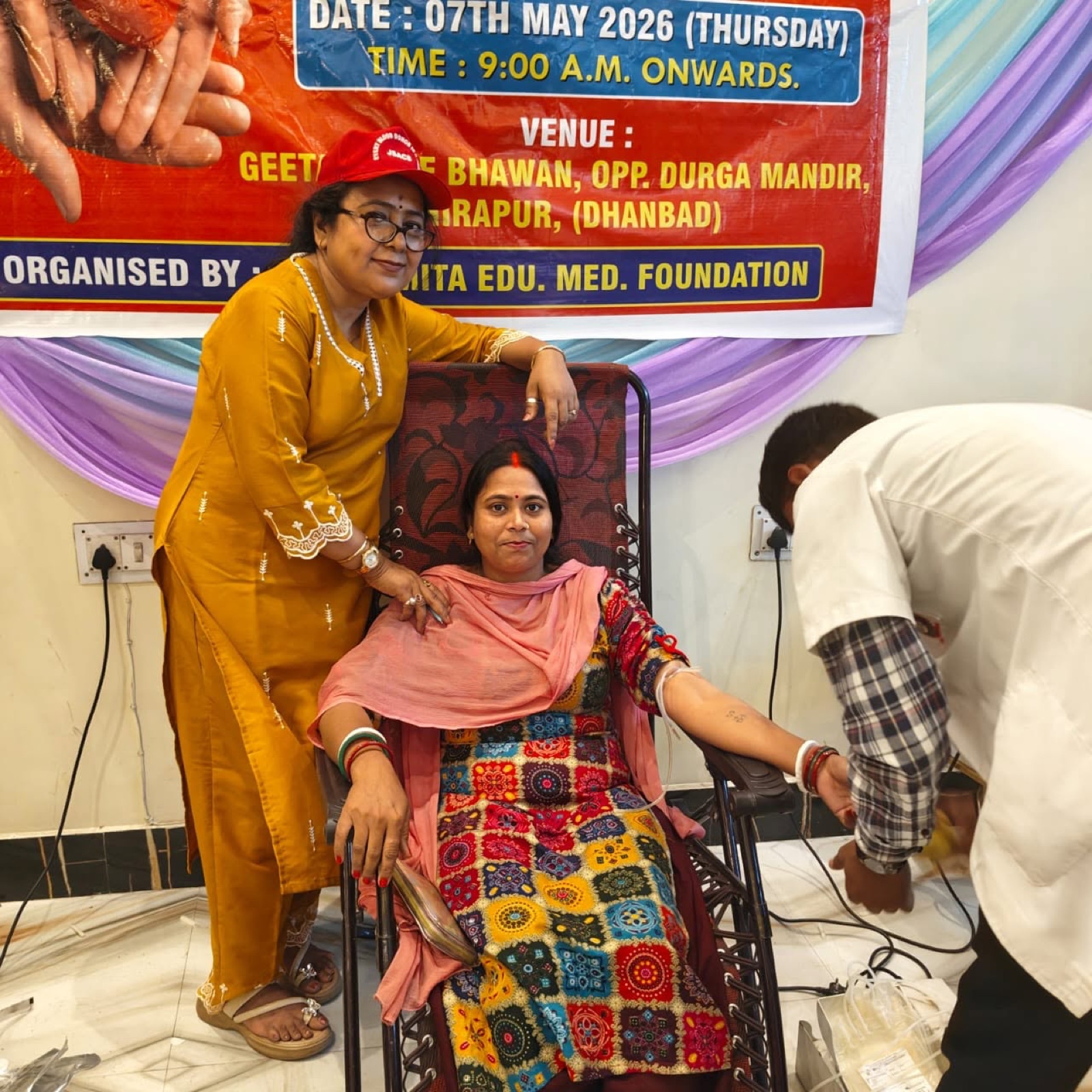 A woman donating blood, supported by a volunteer