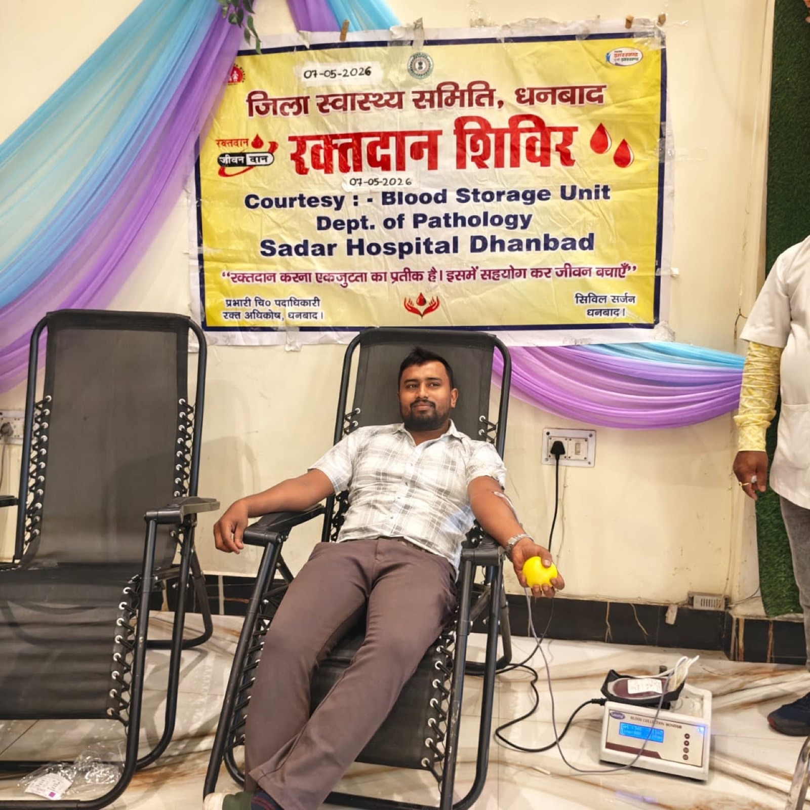 A donor giving blood beneath the camp banner